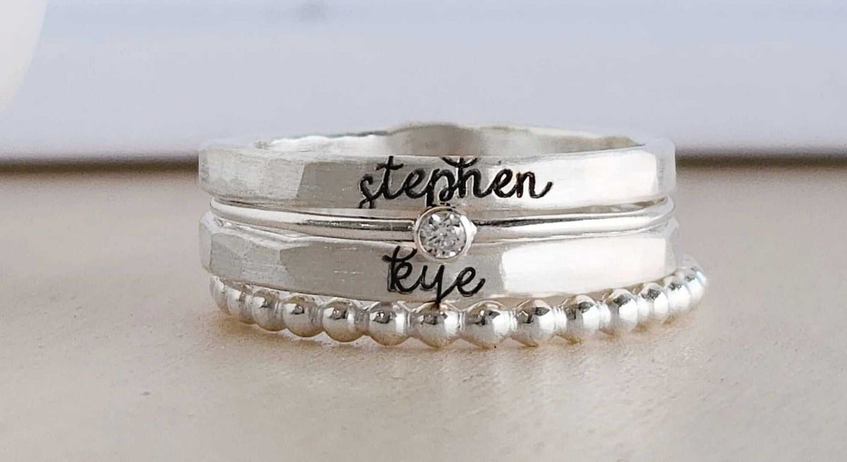 Close-up of elegant personalized jewelry pieces including stackable name rings and engraved bracelets showcasing individuality and timeless style