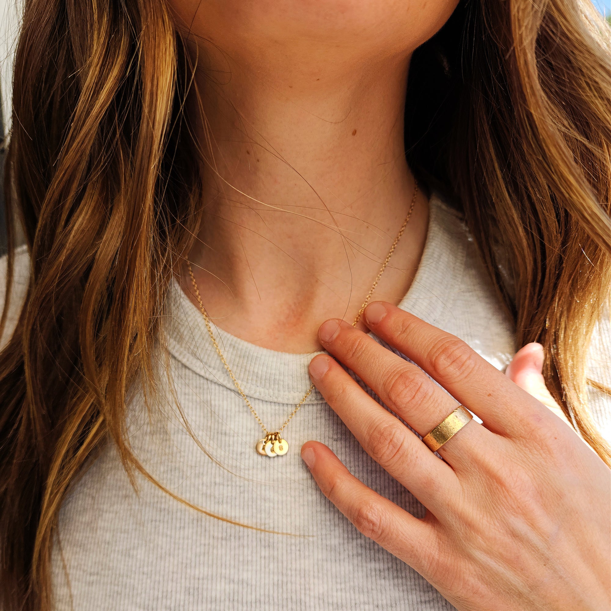 Close-up of woman wearing 14K solid gold dainty initial necklace and ring