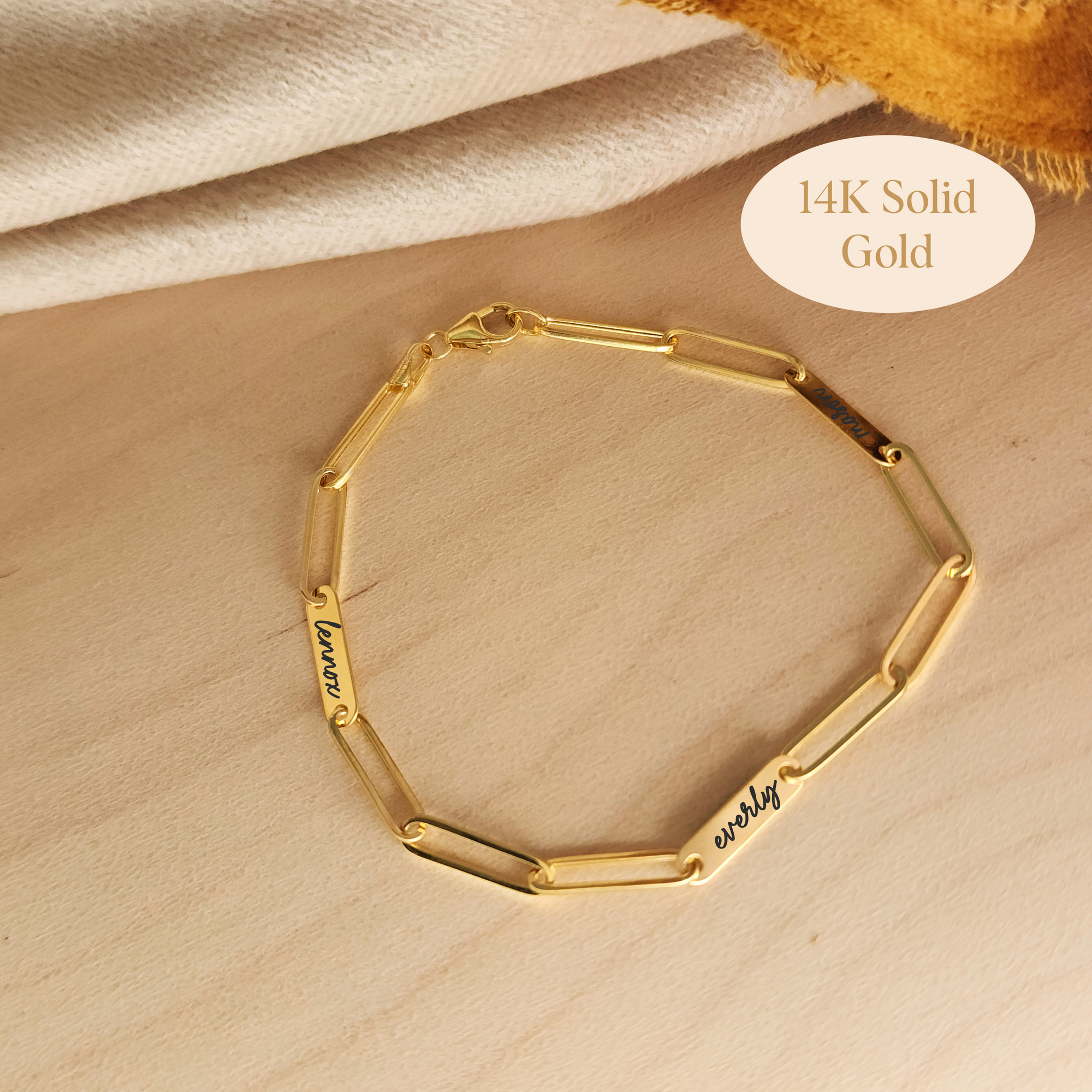 14K solid gold engravable bracelet with personalized name bars shown on wood background