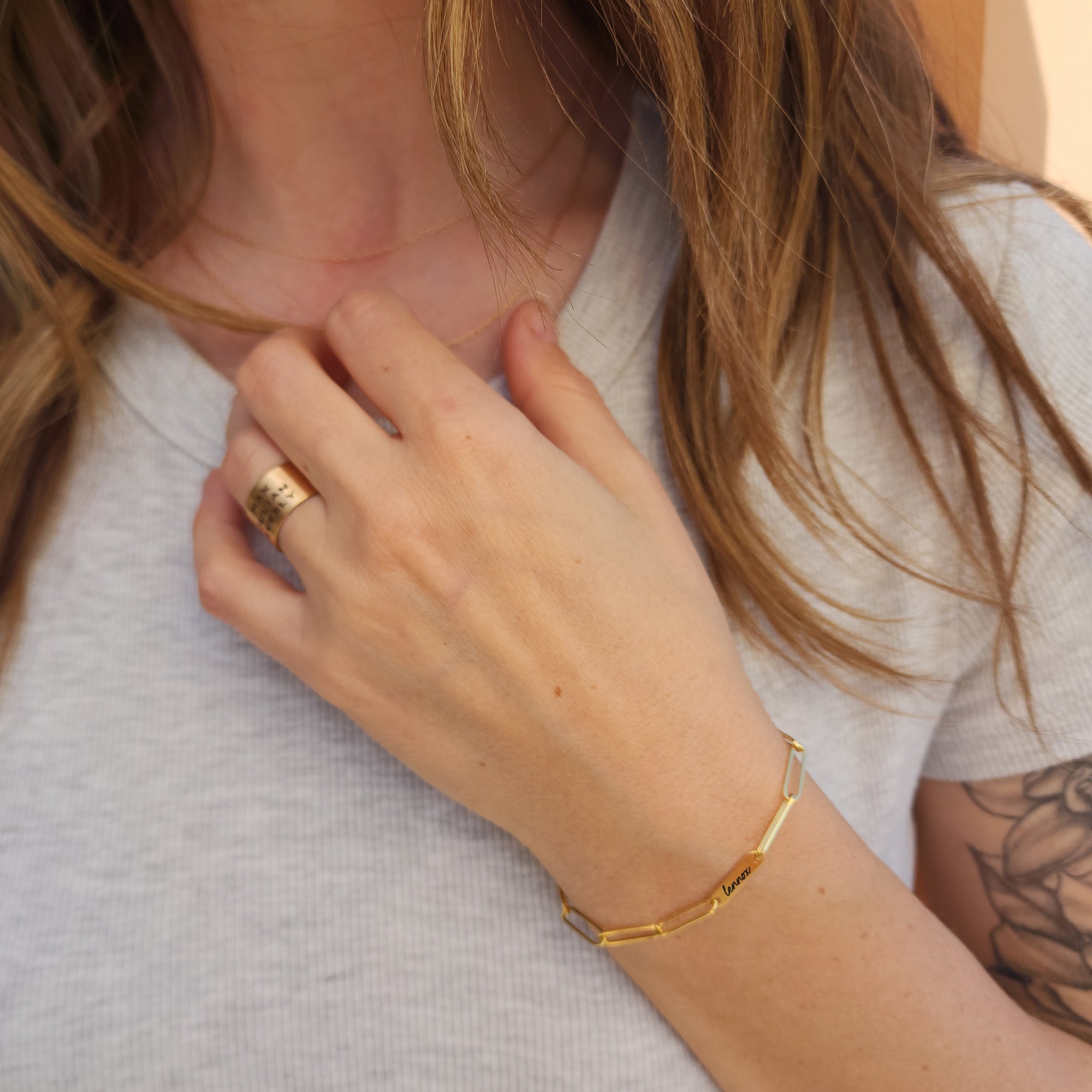 Model wearing 14K solid gold engravable bracelet with custom names engraved on links
