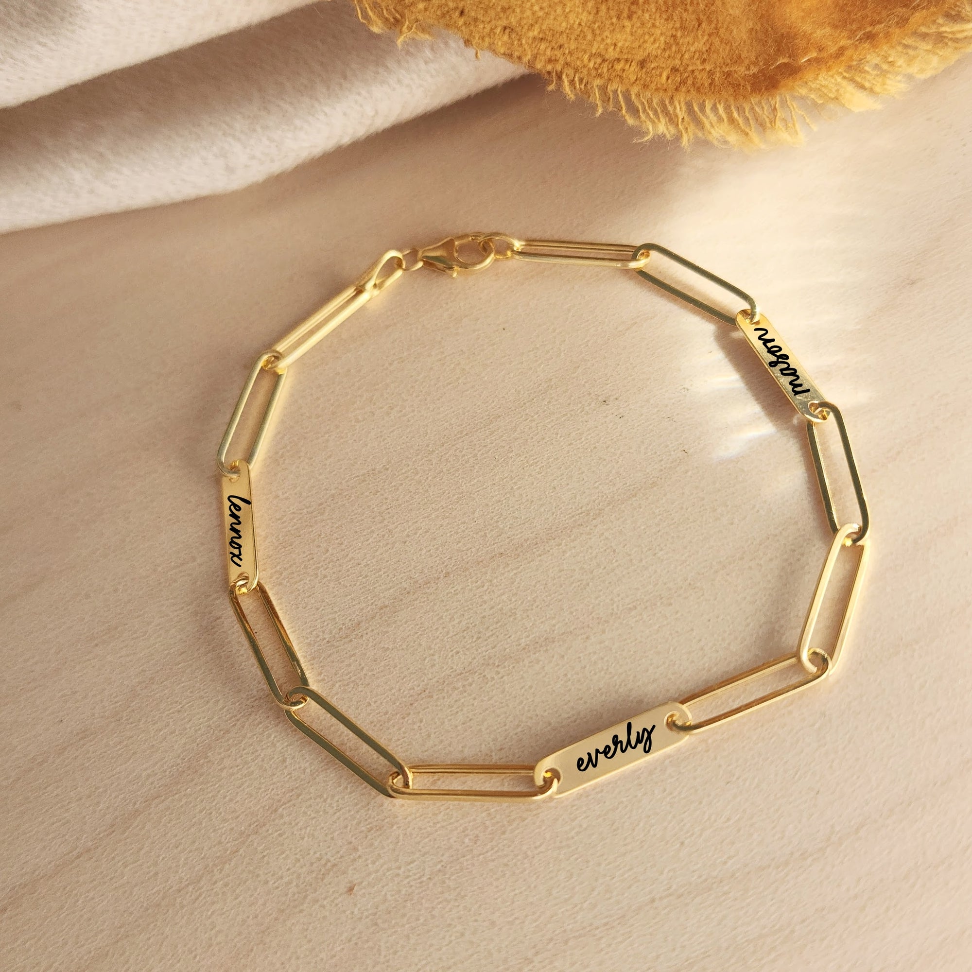 Close-up of 14K solid gold engravable bracelet with name customization on soft fabric