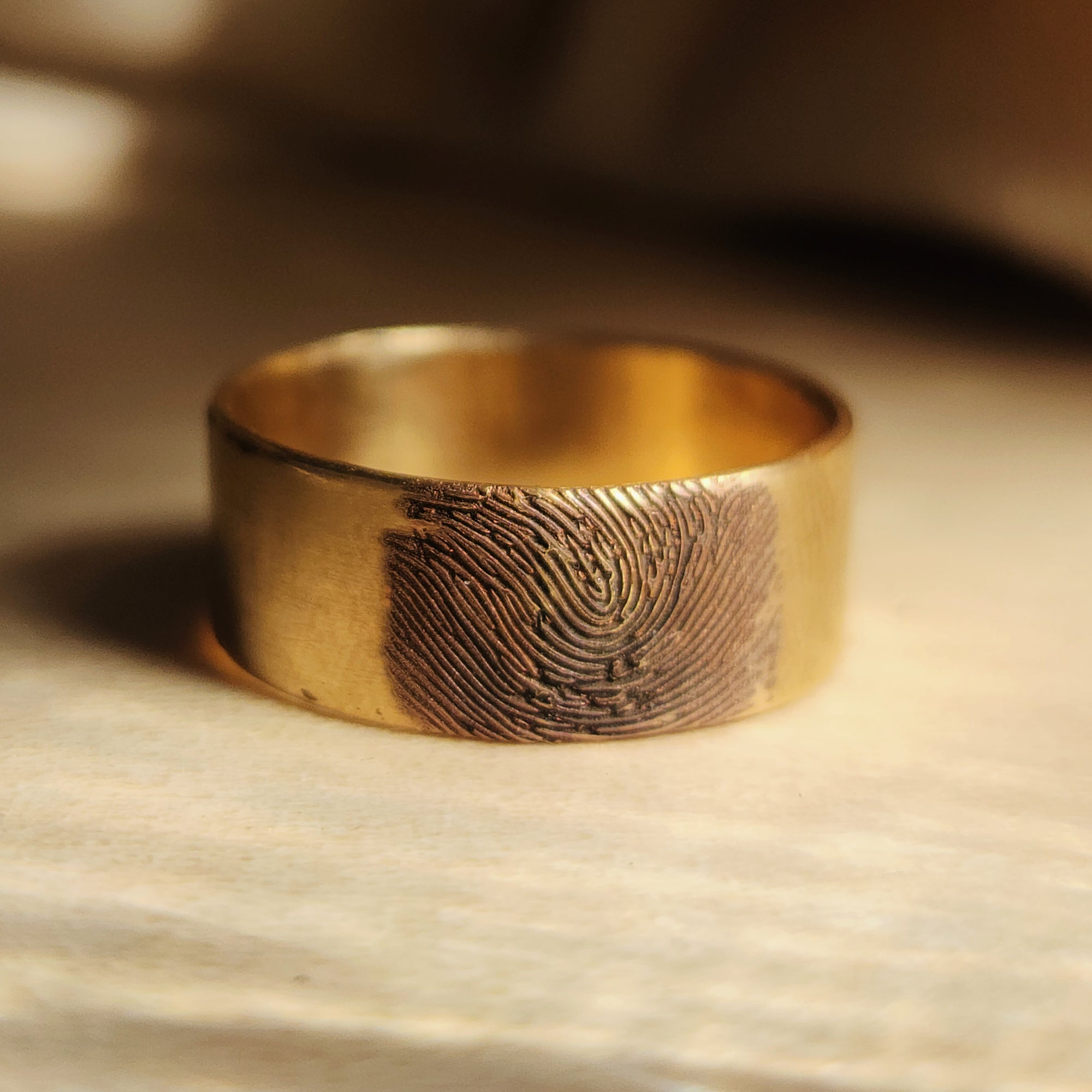 4K solid gold fingerprint band on wood surface with dramatic shadowing
