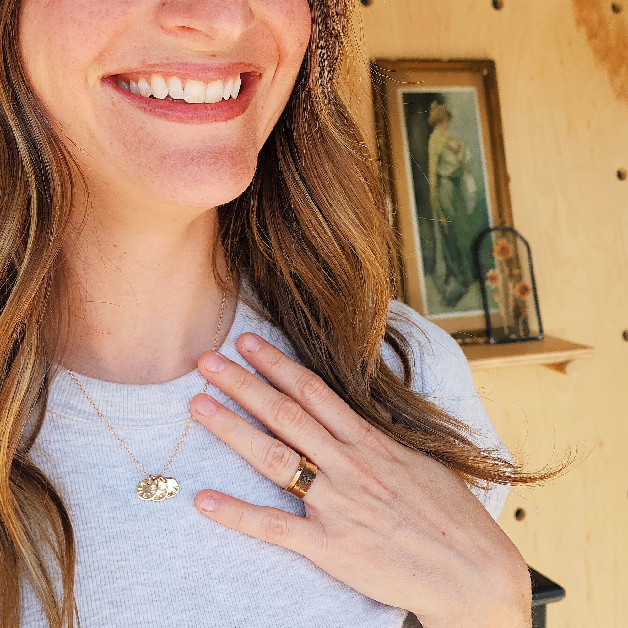 Woman smiling and wearing 14K solid gold fingerprint band with layered gold rings