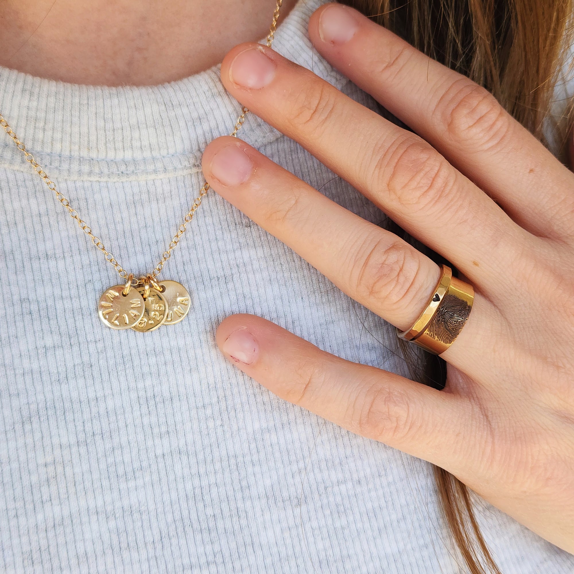 Woman wearing 14K solid gold fingerprint band with layered necklaces and stacked rings
