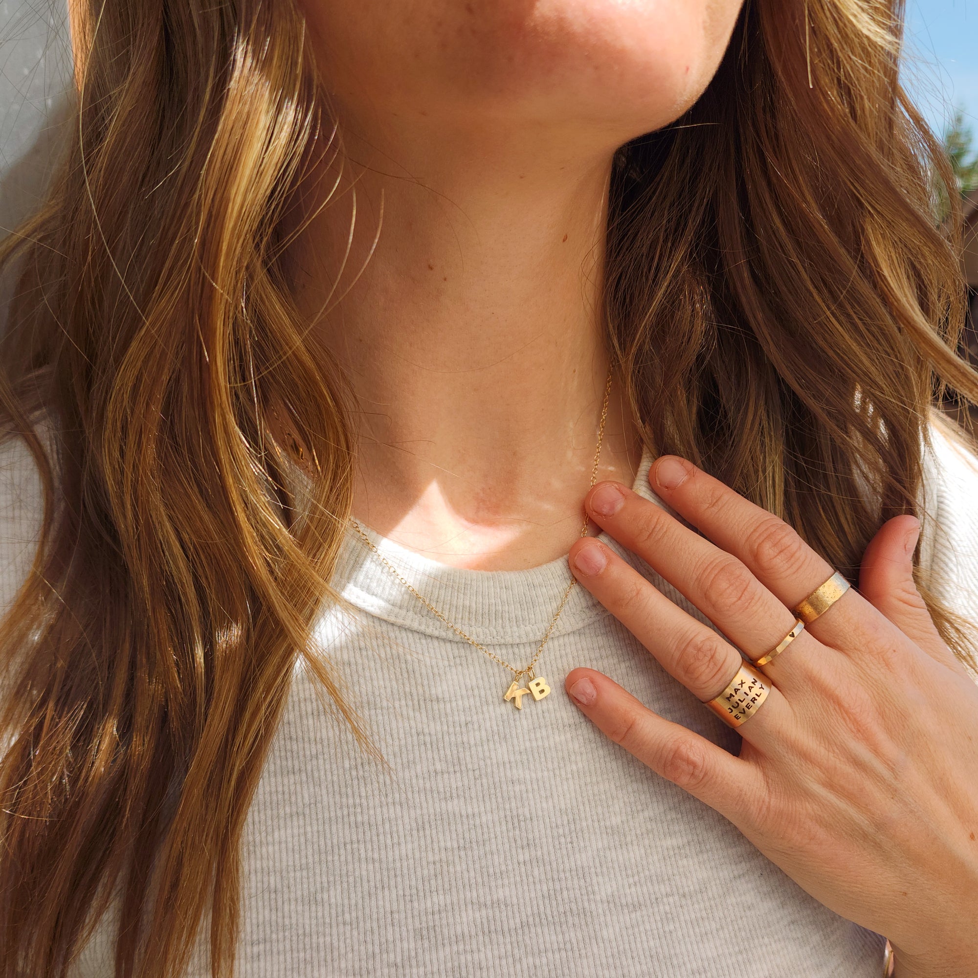 Woman styling 14K solid gold initial pendant necklace with gold stacking rings
