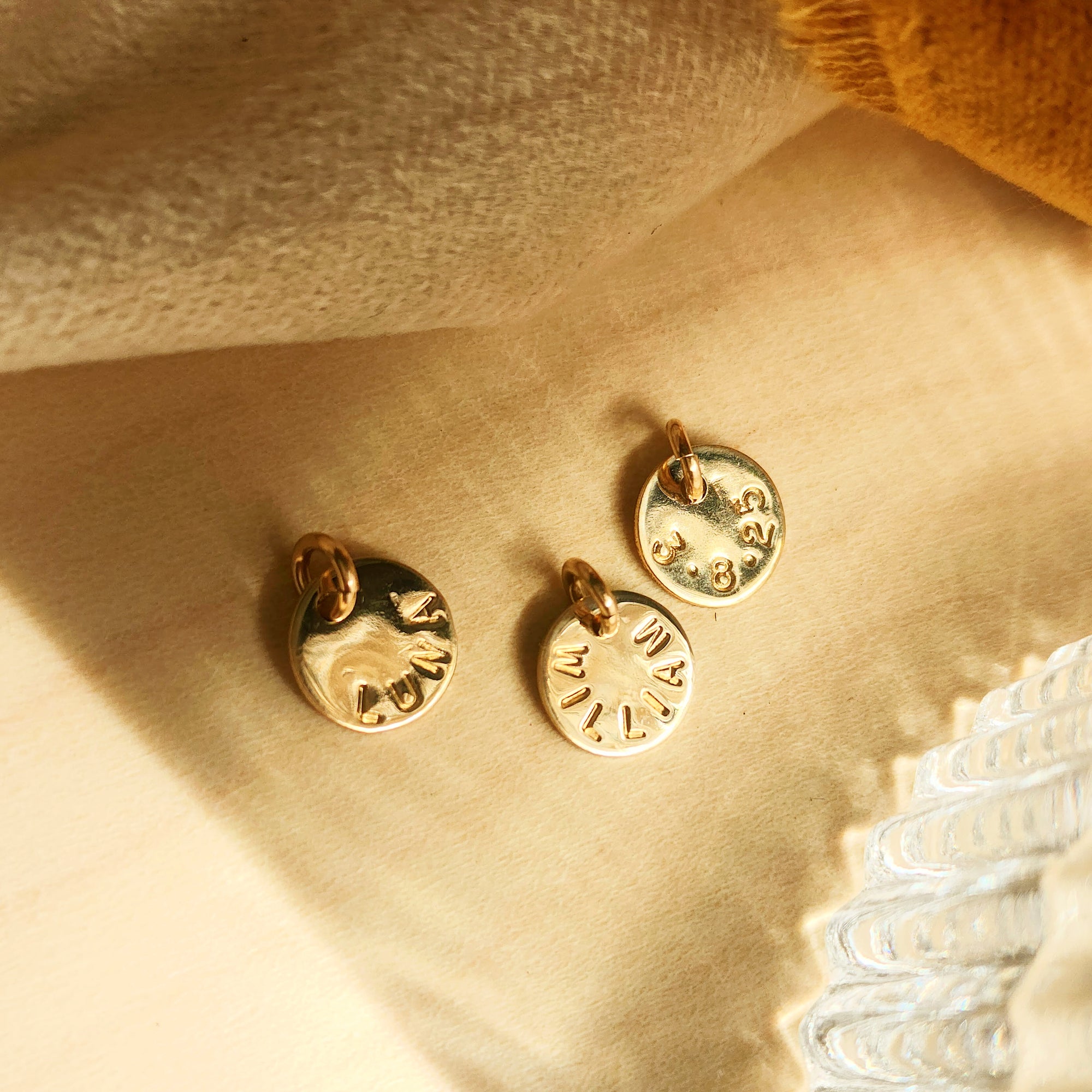 Personalized round tags from 14K solid gold name necklace on beige linen