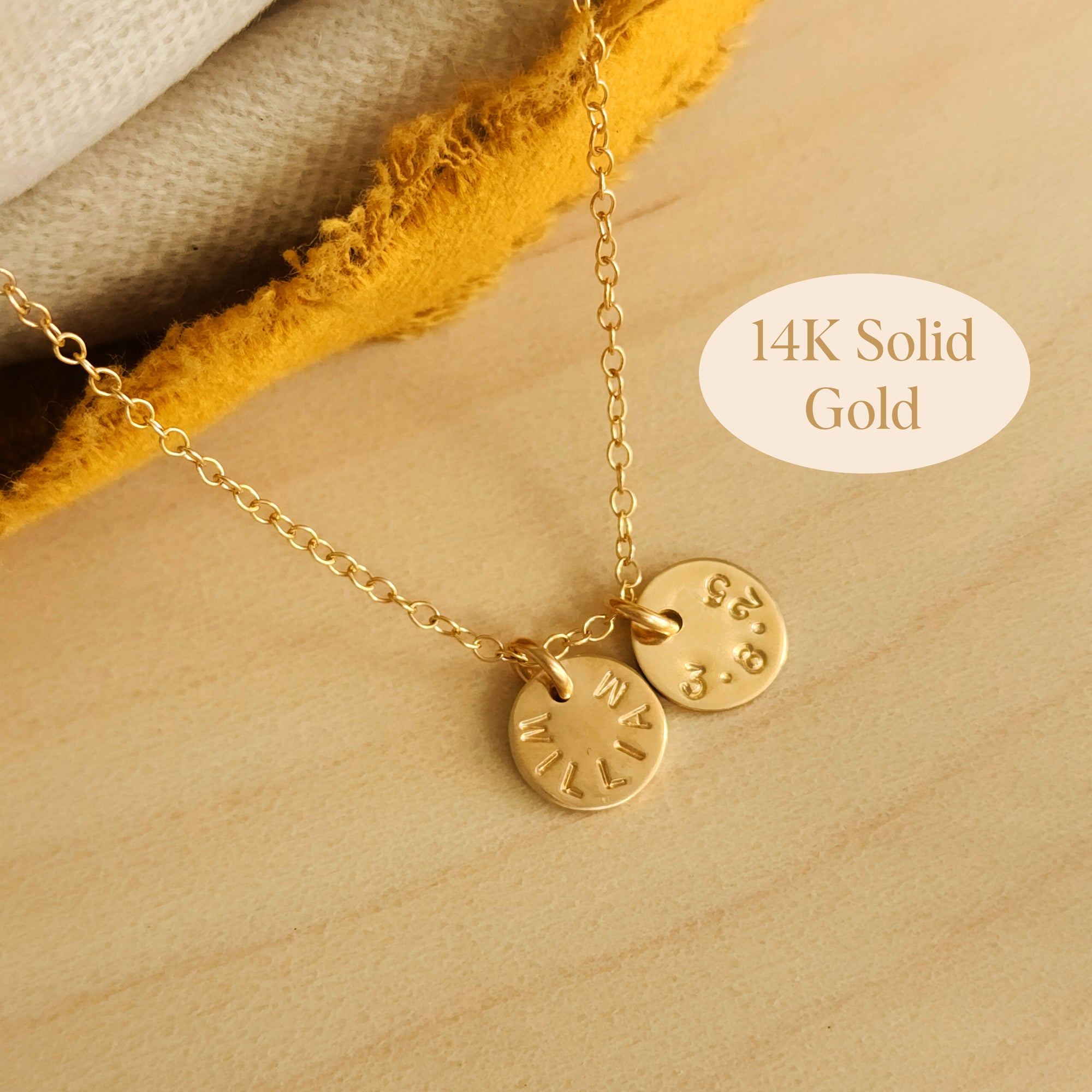 Flat lay of 14K solid gold name necklace with two hand-stamped tags on wood background