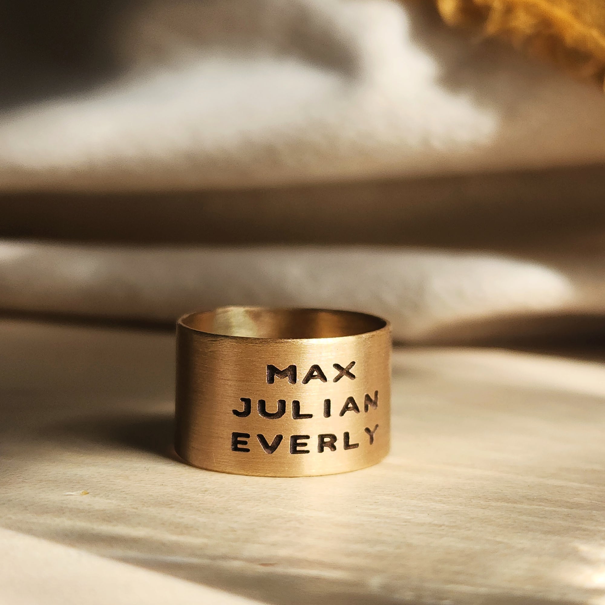 Close-up of 14K solid gold personalized band with engraved text, styled on golden fabric