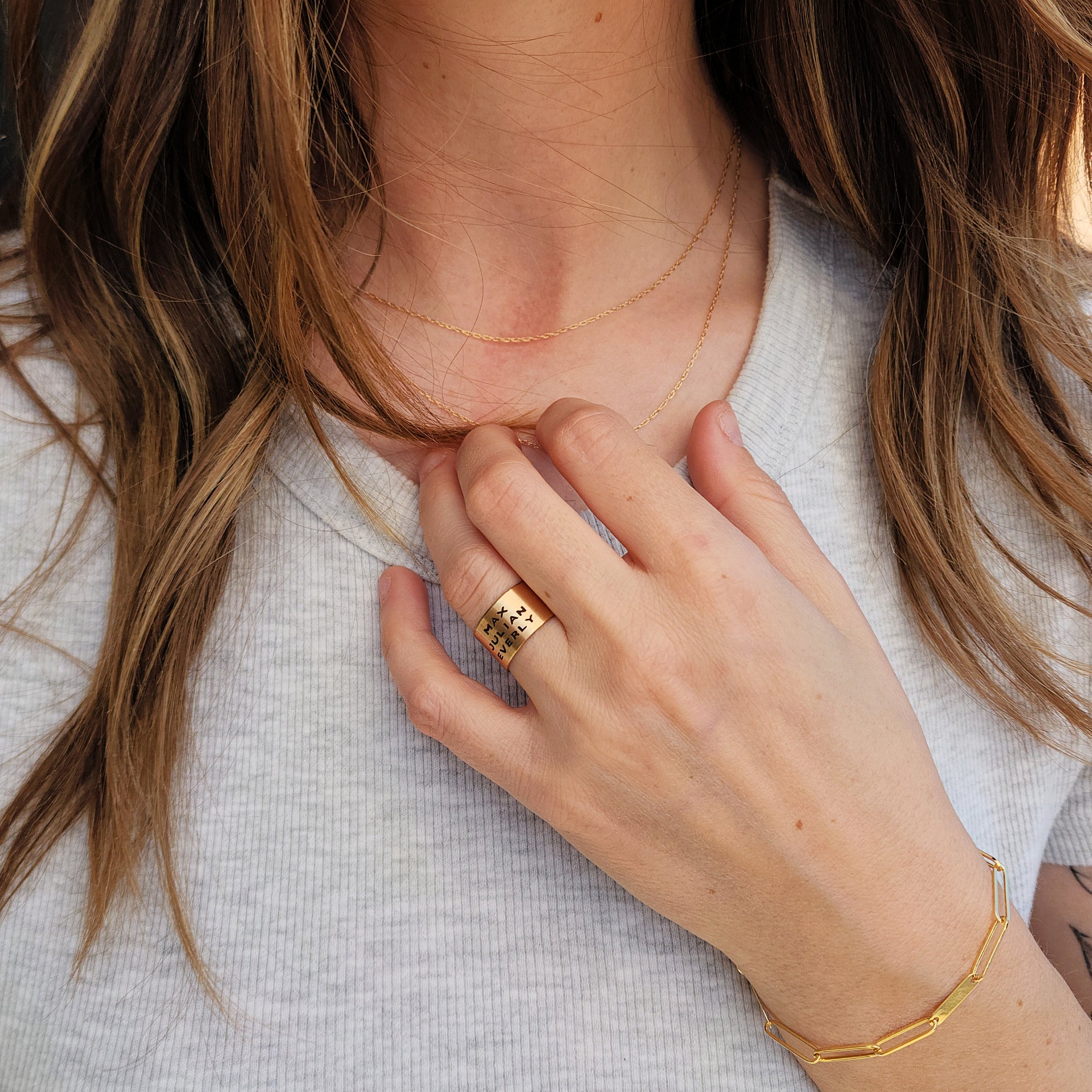 Model showcasing 14K solid gold personalized band with hand placed over chest