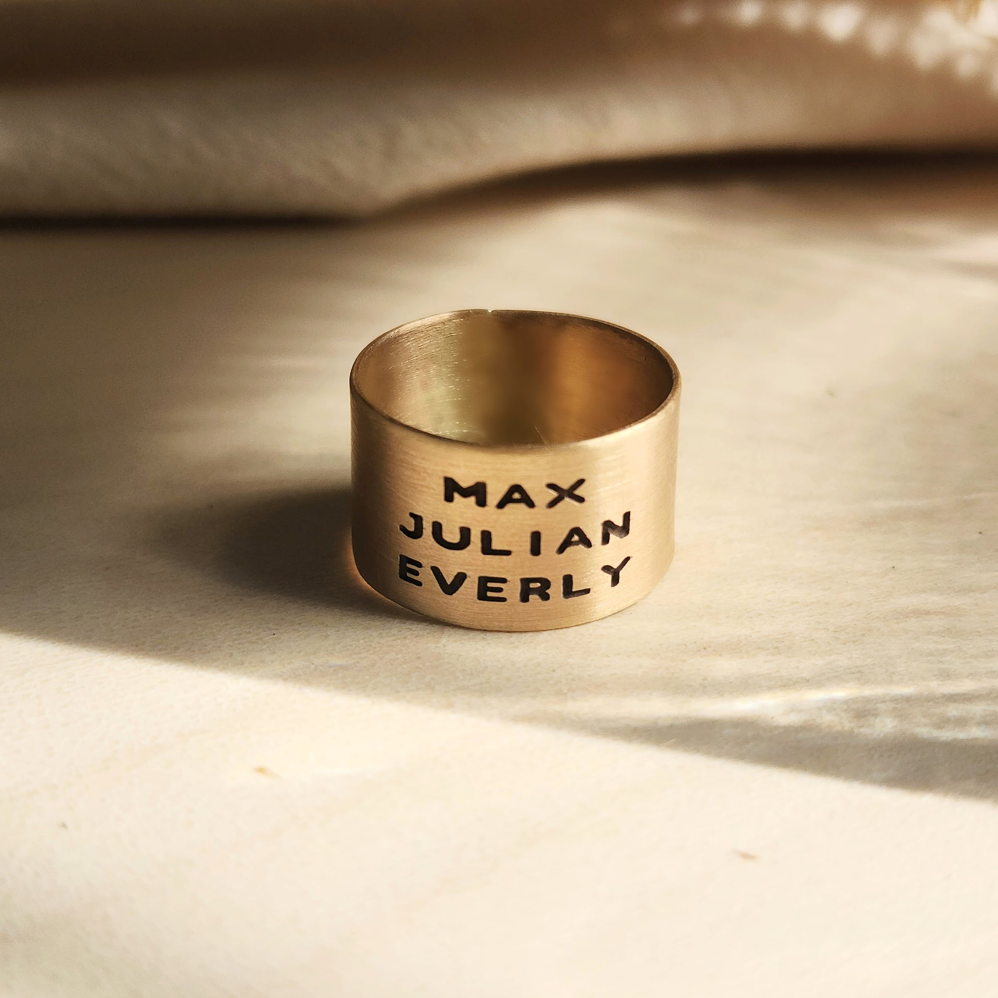 14K solid gold personalized band shown with engraved names in warm natural lighting