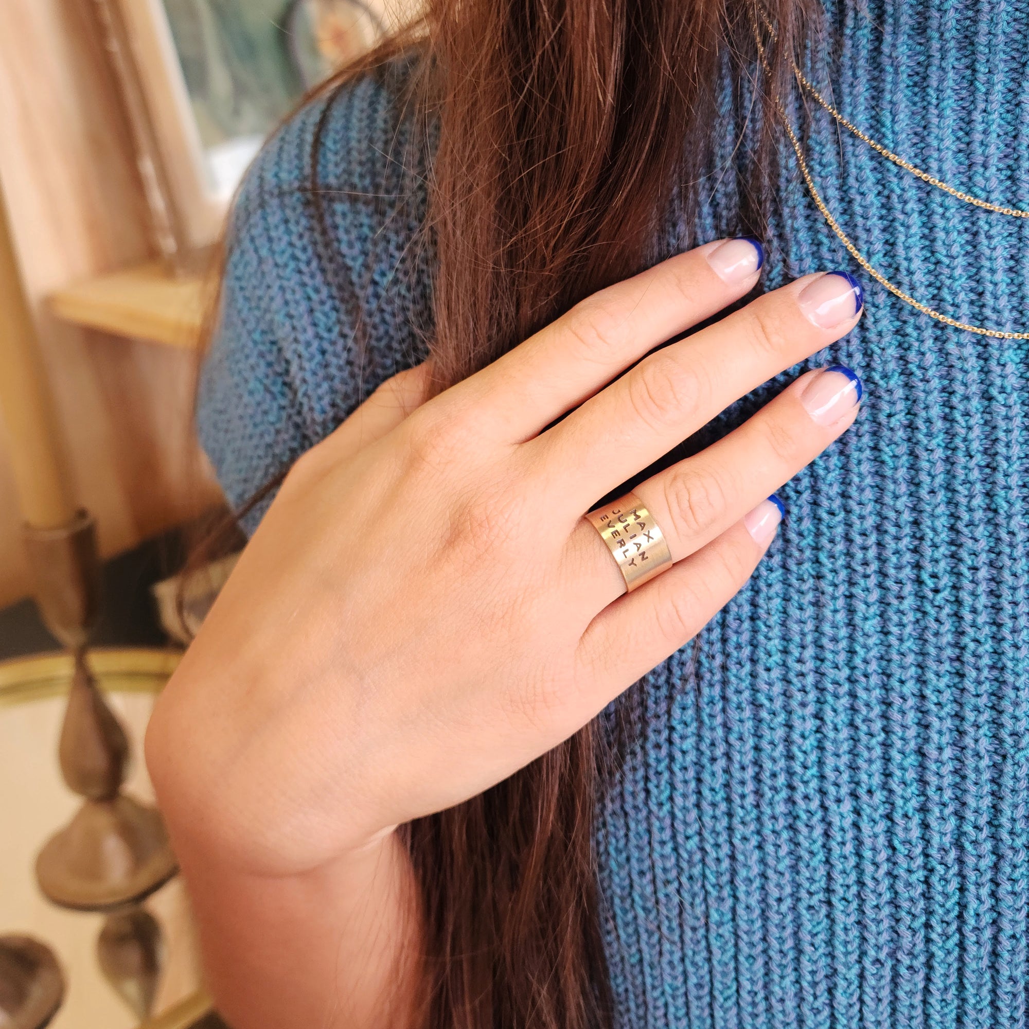 14K solid gold personalized band worn on model's hand with blue knit sweater