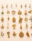 Flat lay of 18k gold plated PVD add-on charms including hearts, crosses, butterflies, and pearls arranged on a neutral background
