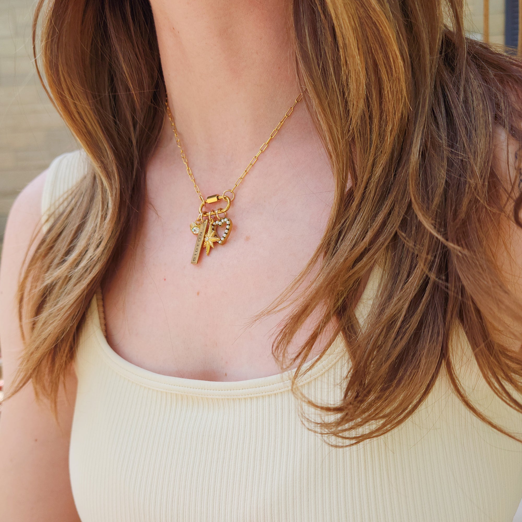 Model wearing 18k gold plated PVD add-on charms on gold chain necklace with butterfly and heart charms