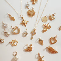Close-up of 18k gold plated PVD add-on charms on dainty gold chain featuring star, heart, sun, and pearl charms