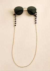 Sunglasses with a beaded chain on a beige background