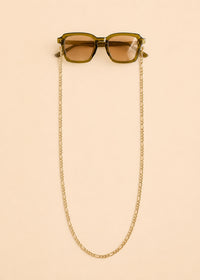 Sunglasses with a gold chain on a beige background