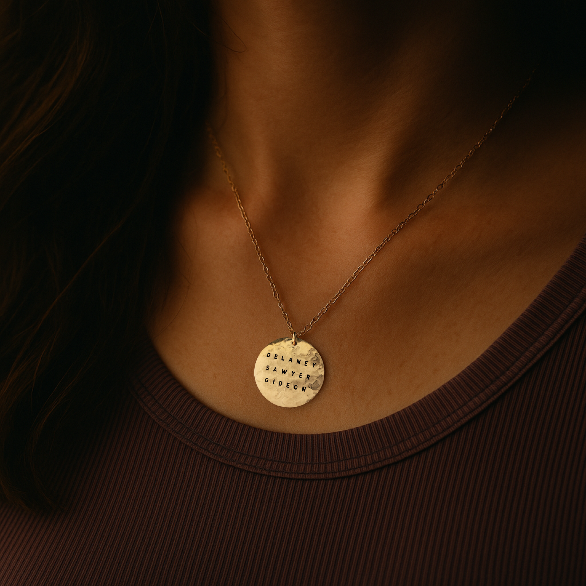 Gold necklace with a round pendant on a dark background