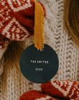 Black round ornament with 'THE SMITHS 2025' text, surrounded by red and white patterned fabric and yellow tassel.