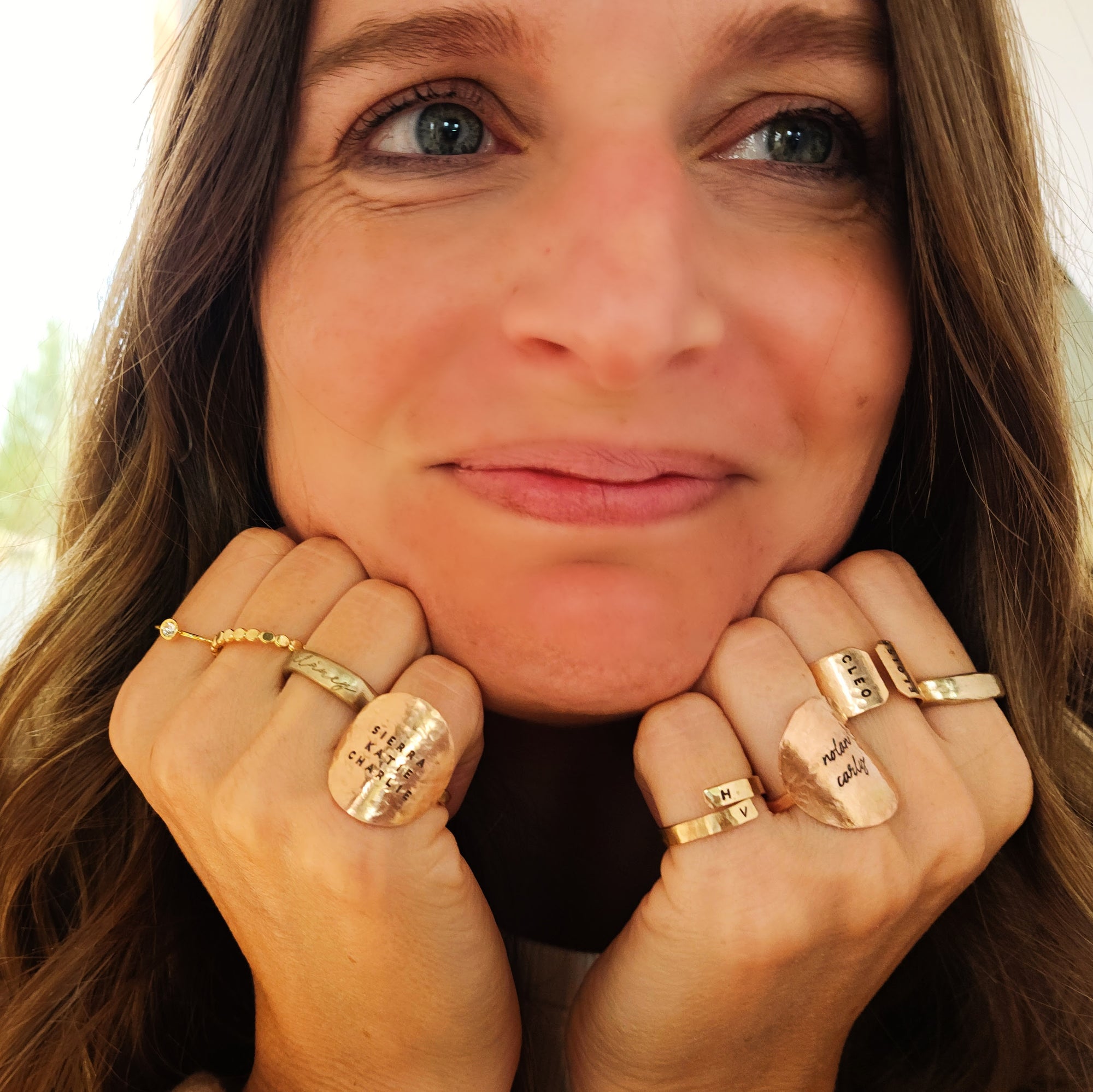 Woman wearing multiple gold rings on her fingers with a blurred background