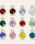 Colorful gemstone charms with gold frames for each month of the year on a white background.