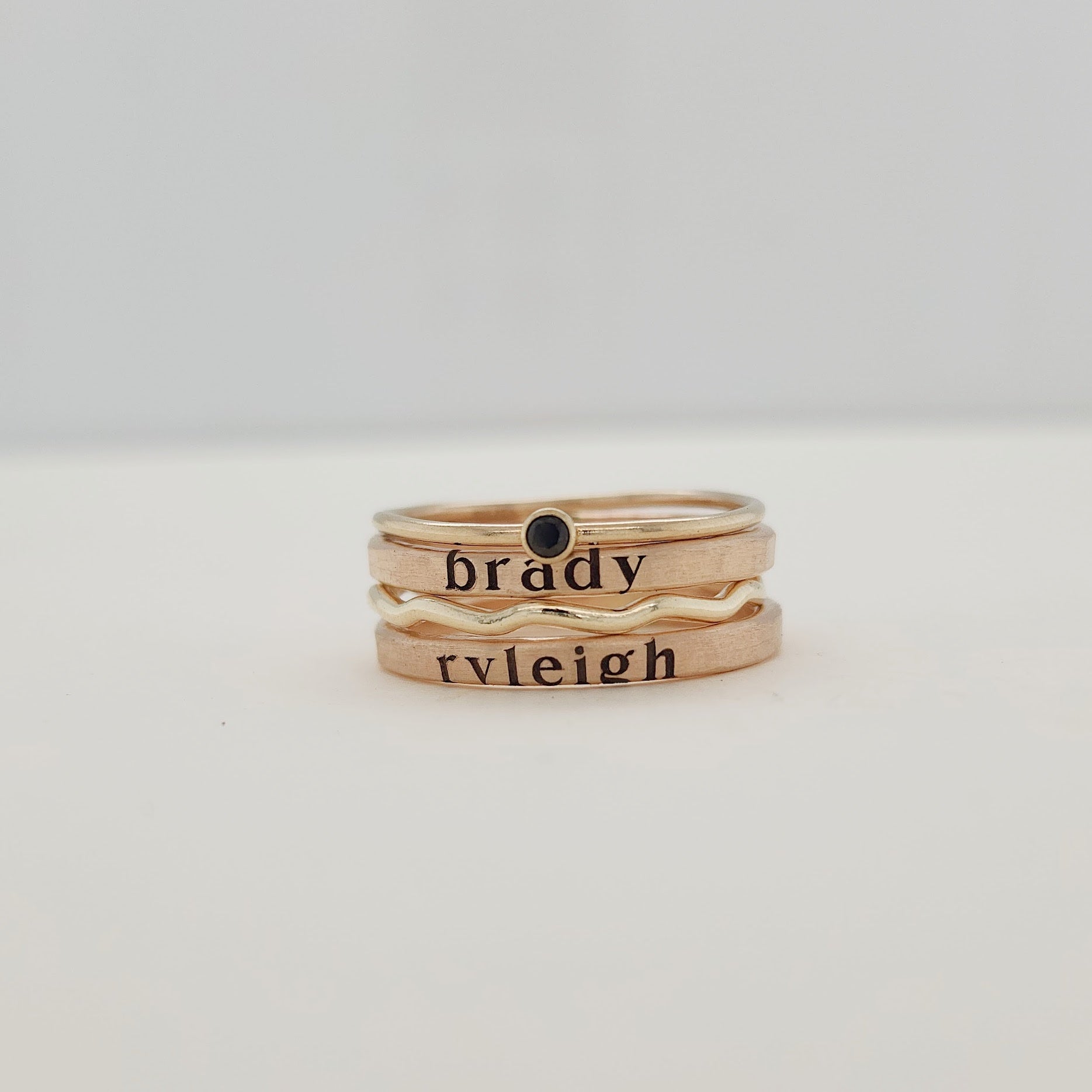 A person's hand showcasing a stack of gold-filled rings, with the focus on the rings' texture and shine.