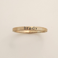 Gold ring with 'brady' engraved on a beige background