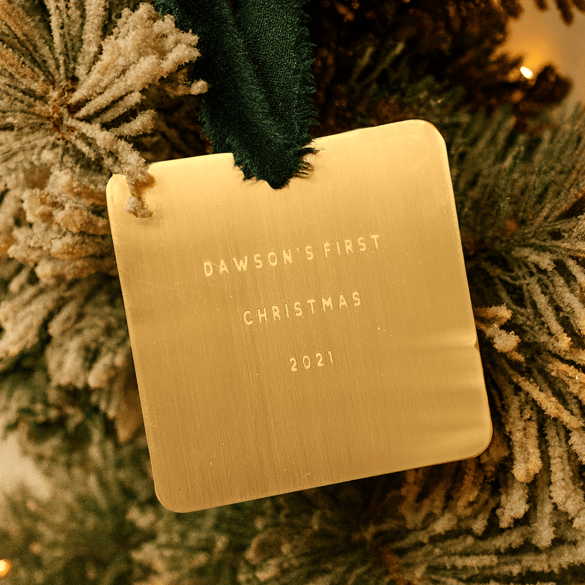Gold ornament with 'Dawson's First Christmas 2021' text on a Christmas tree.