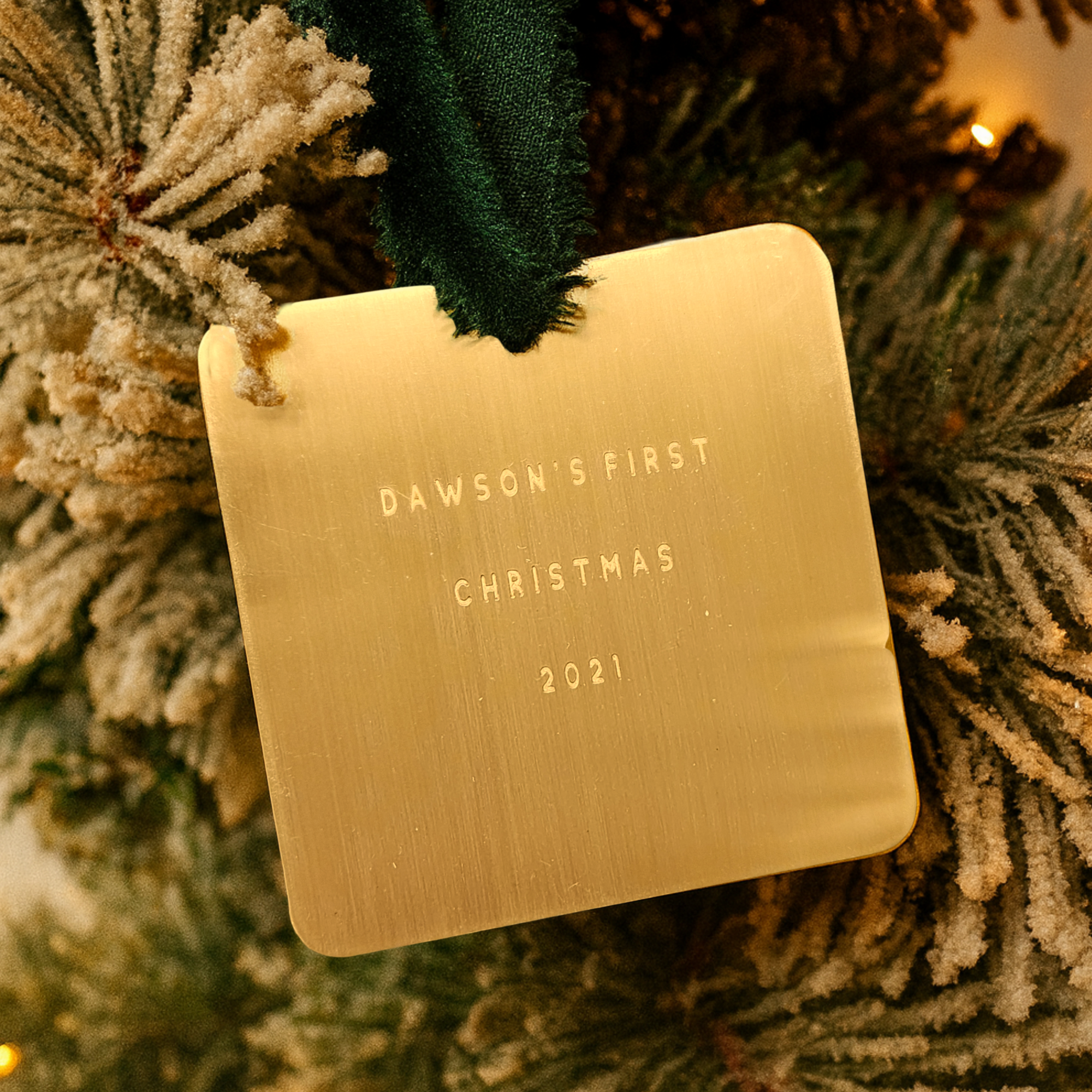 Gold ornament with 'Dawson's First Christmas 2021' text on a Christmas tree.