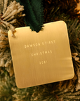 Gold ornament with 'Dawson's First Christmas 2021' text on a Christmas tree.