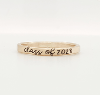 A gold-colored stacking ring with 'class of 2028' engraved on it, displayed against a white background.