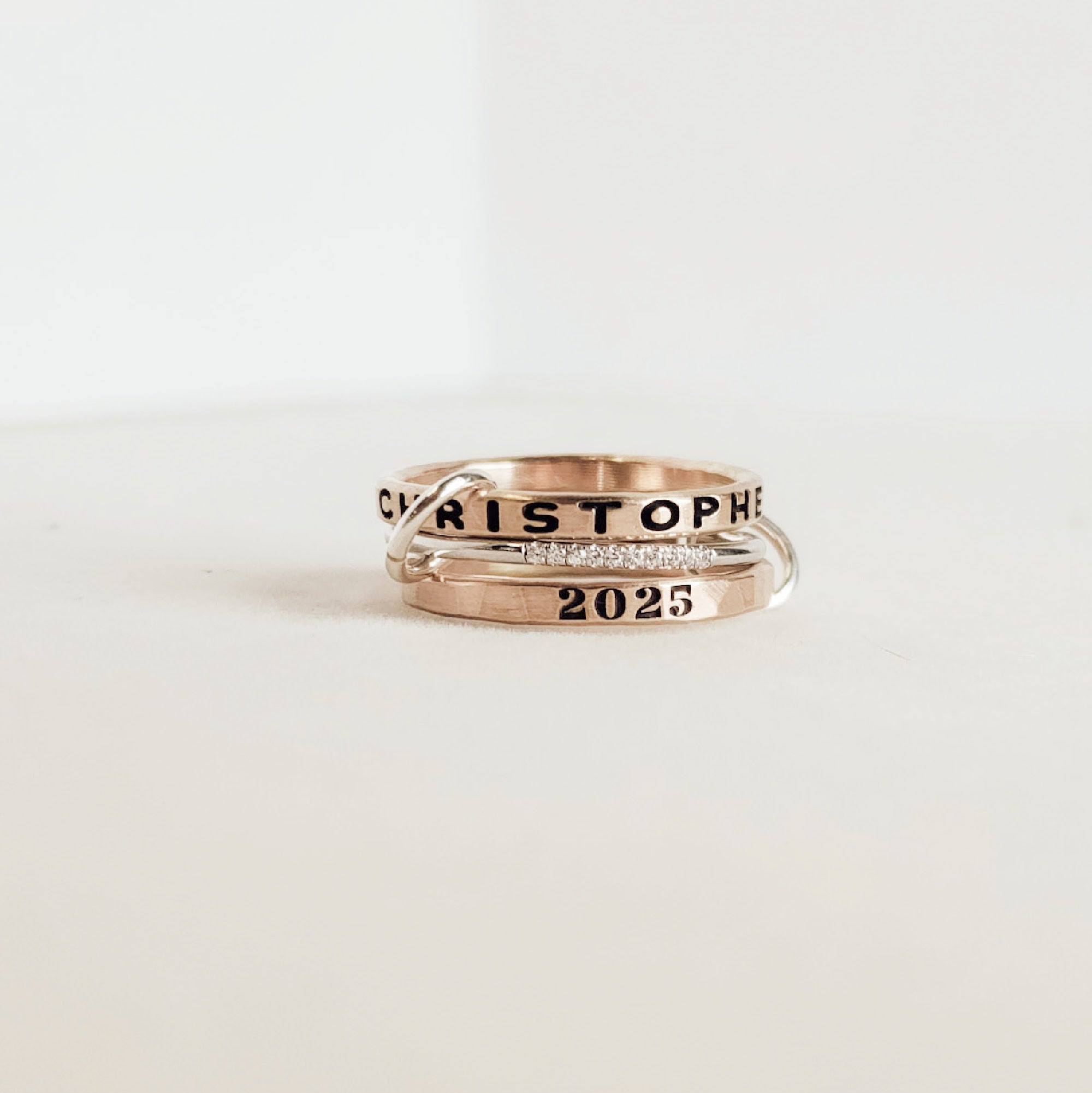 Two gold rings with engraved text on a white background