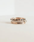 Two gold rings with engraved text on a white background