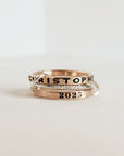 A set of personalized rings on a white background, featuring a gold-filled band with the name 'Christopher' and the year '2025' inscribed on it.
