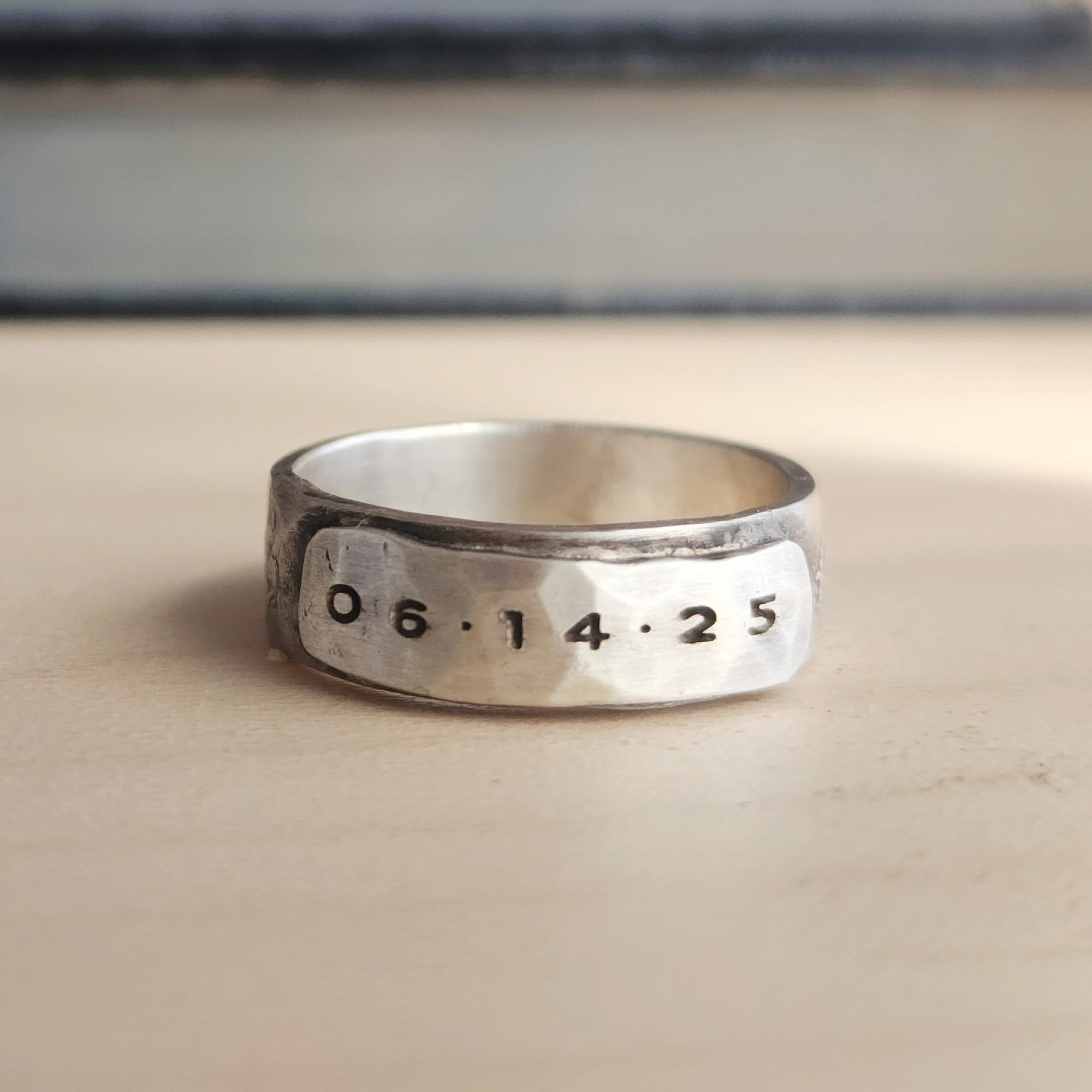 Silver ring with engraved numbers on a wooden surface