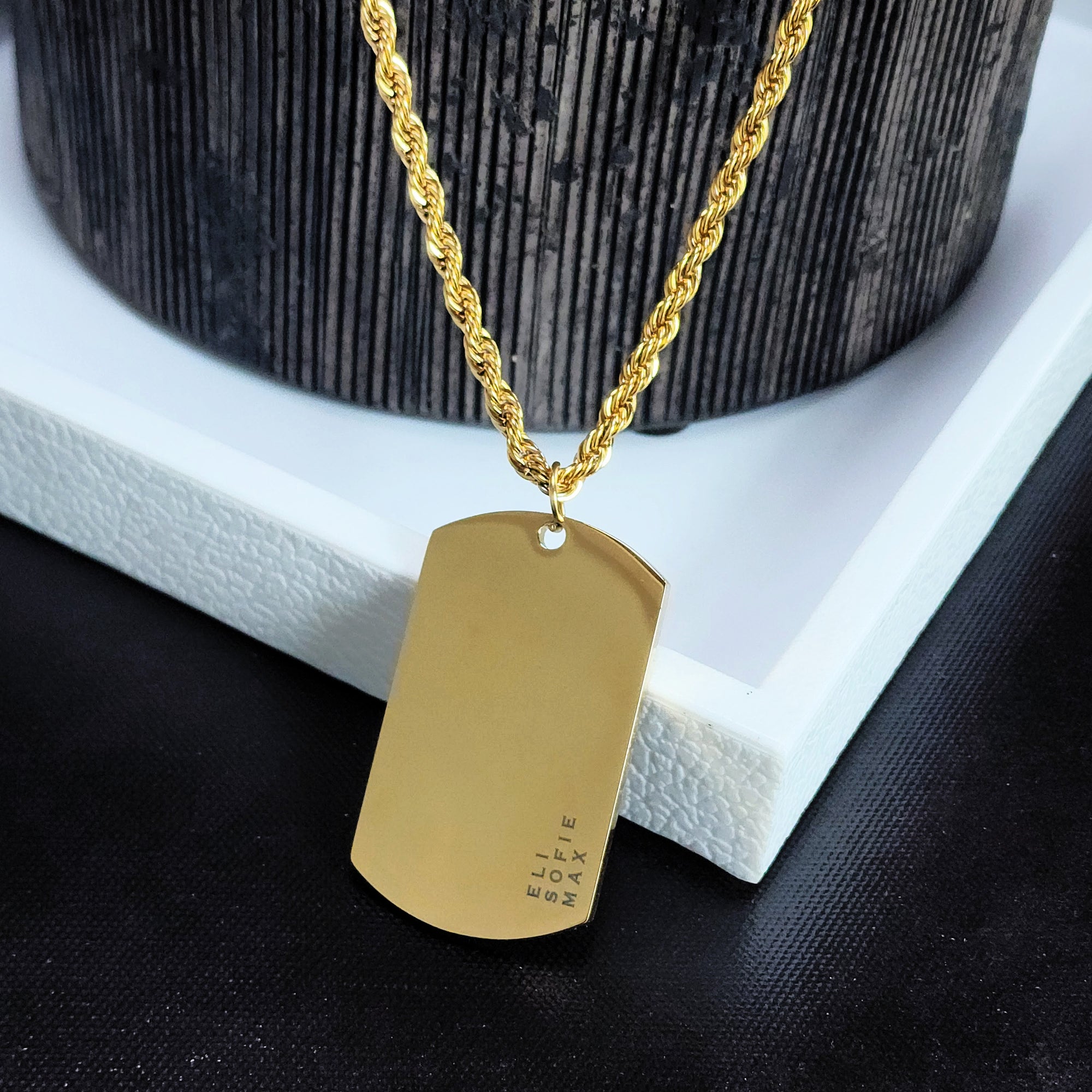 Gold dog tag necklace on a textured surface