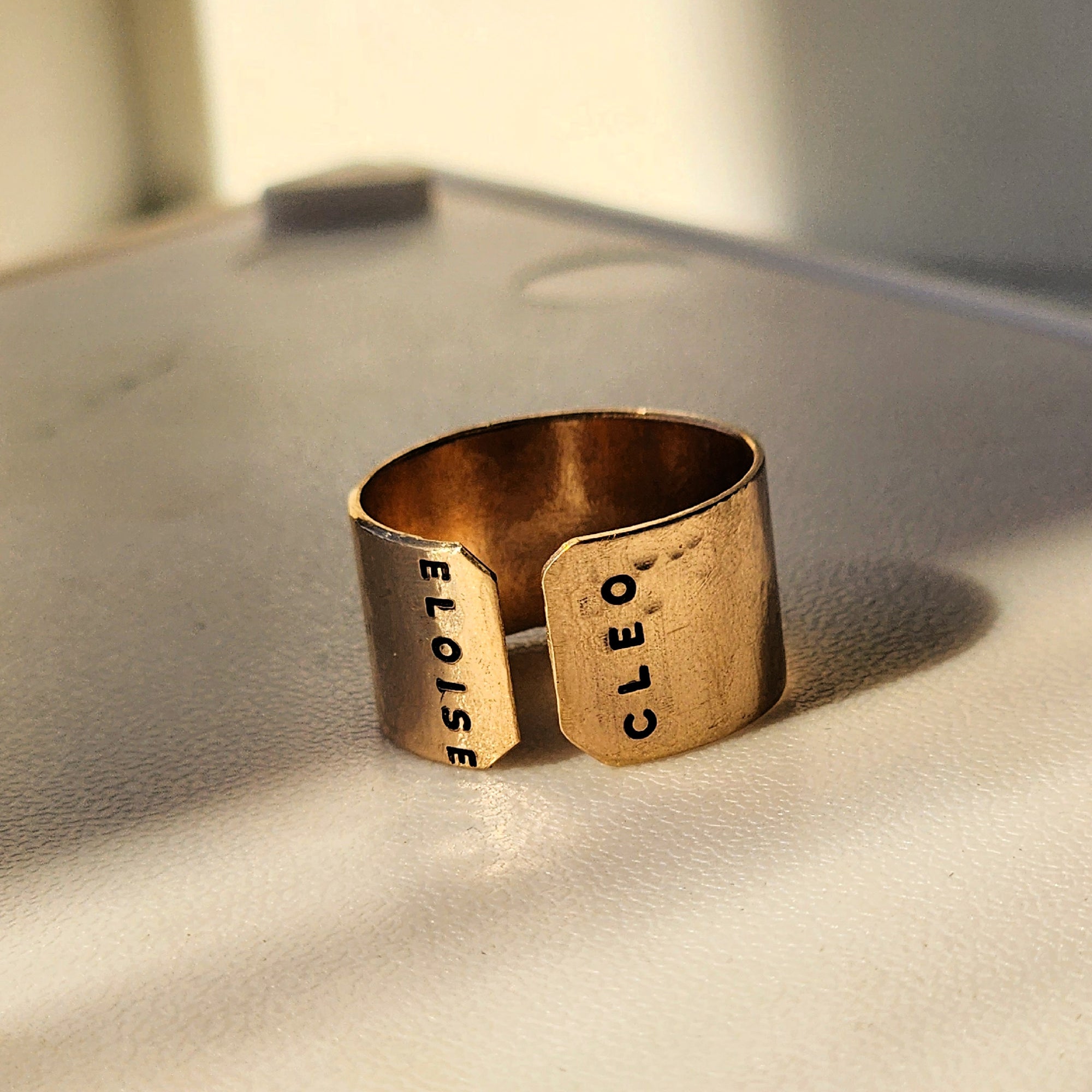 Detailed close-up of engraved gold name cuff ring showing stamped letters