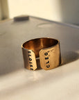 Detailed close-up of engraved gold name cuff ring showing stamped letters