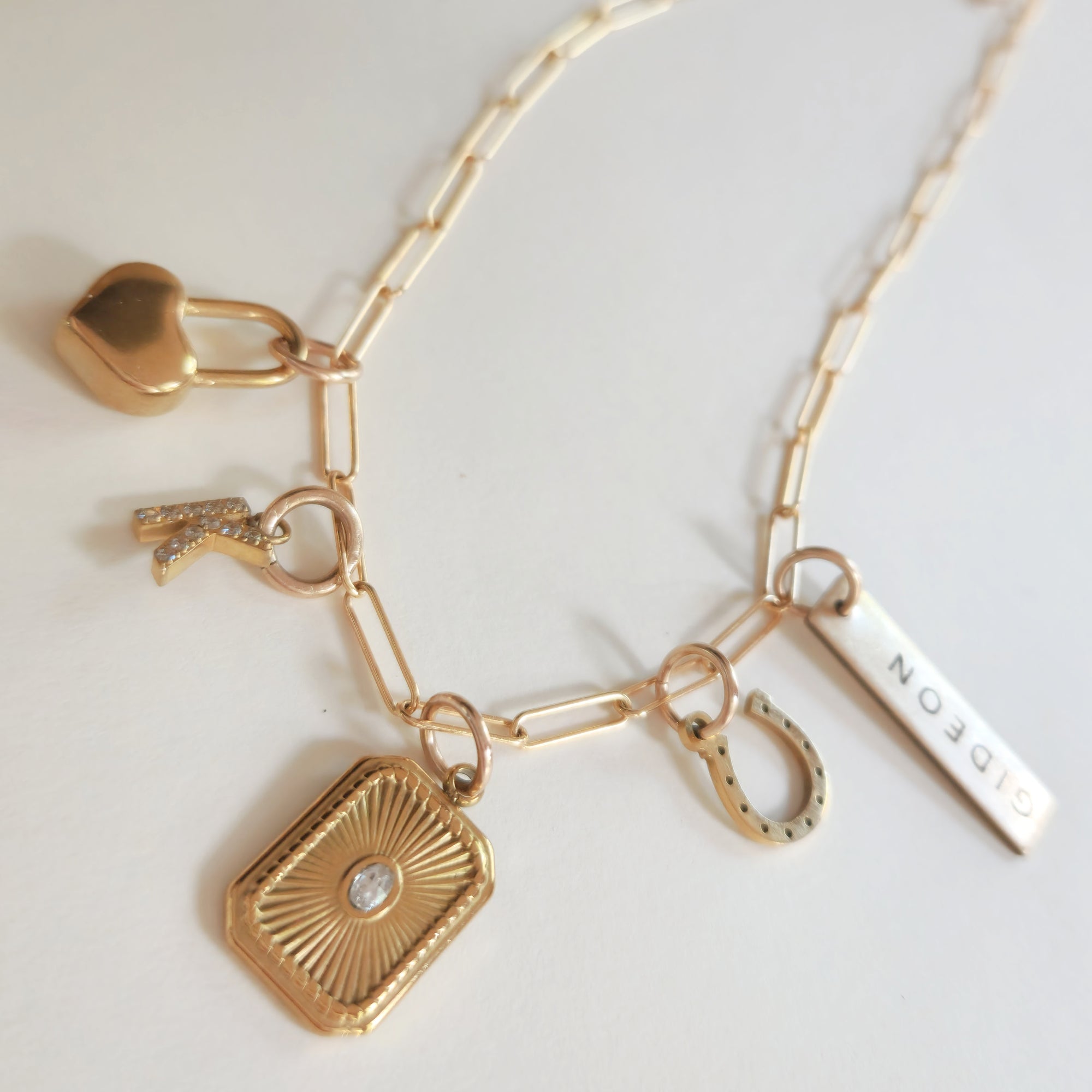 Gold necklace with various charms on a light background