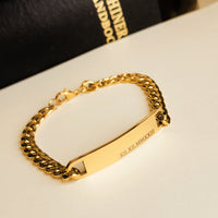 Gold chain bracelet with engraved design on a white surface