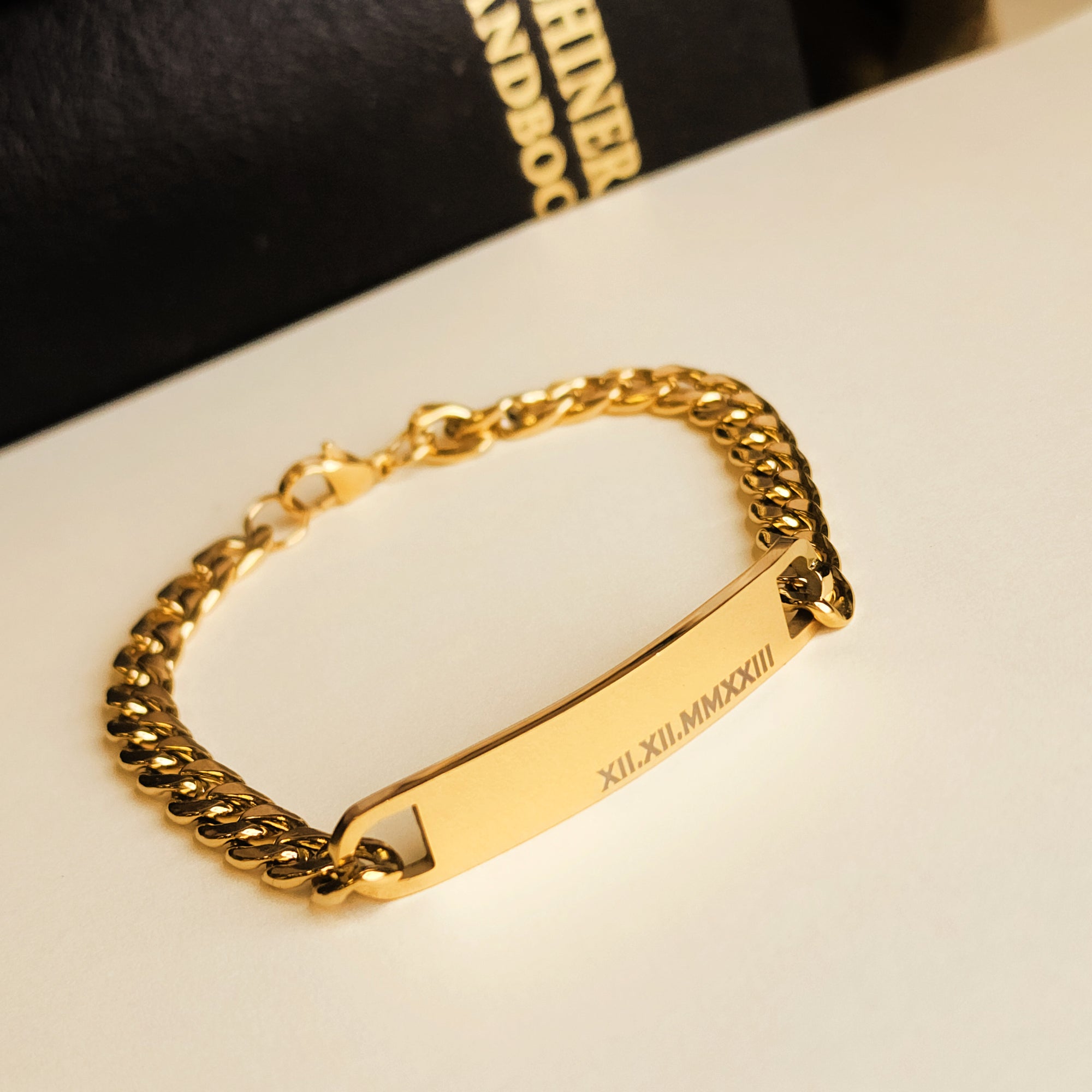Gold chain bracelet with engraved design on a white surface