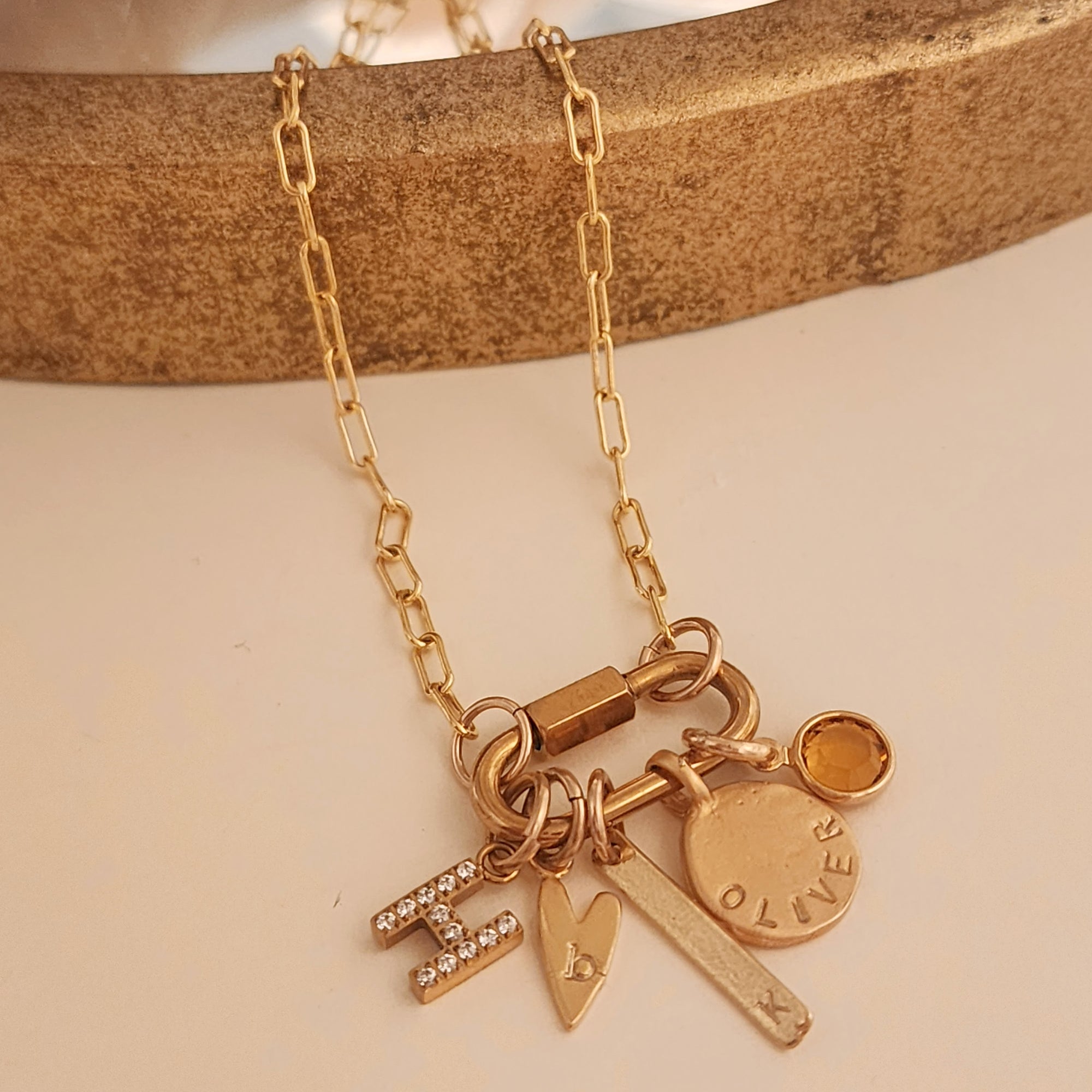 Gold necklace with various charms on a beige background