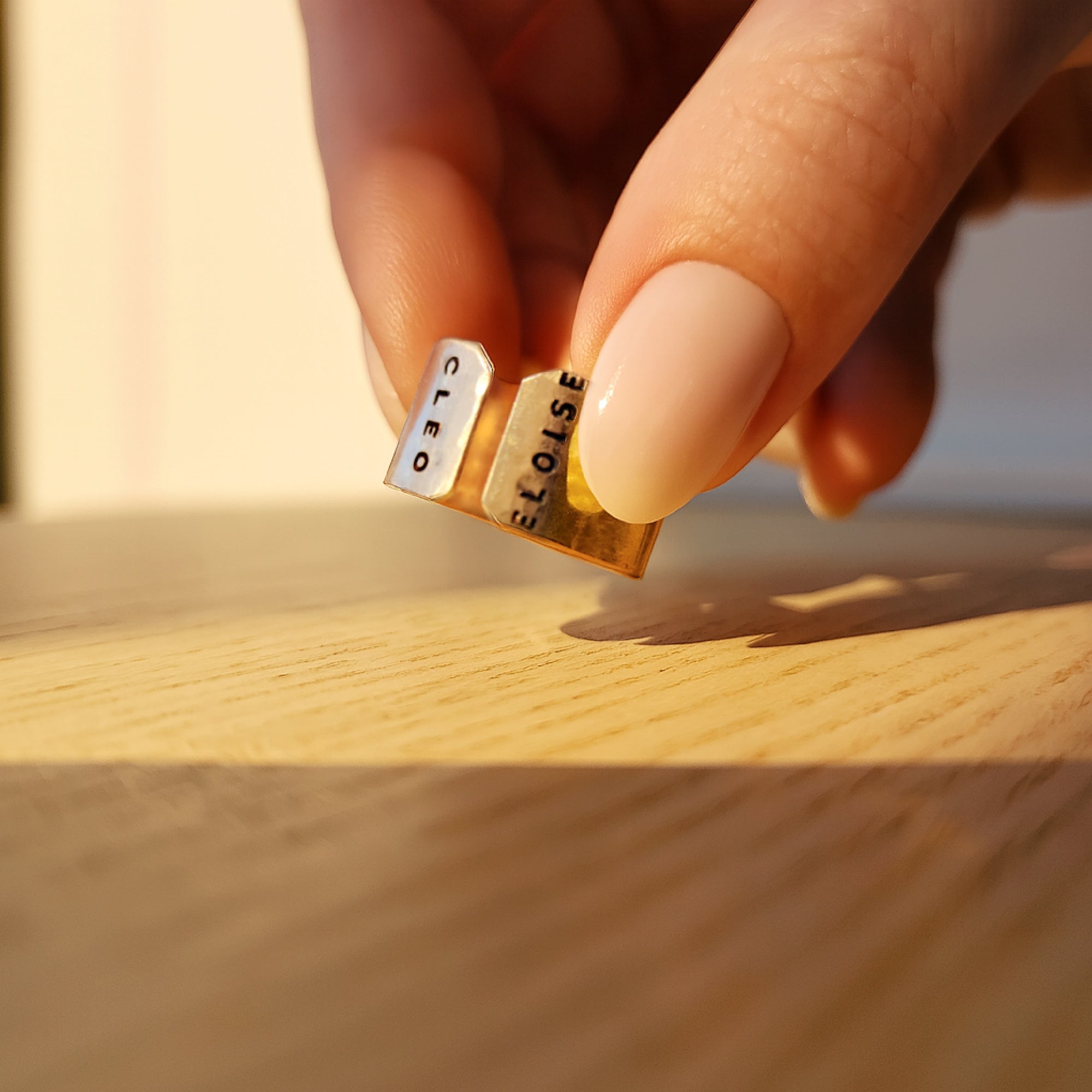 Personalized gold cuff ring engraved with names worn on woman’s hand