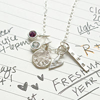 Silver necklace with charms on a piece of paper with writing
