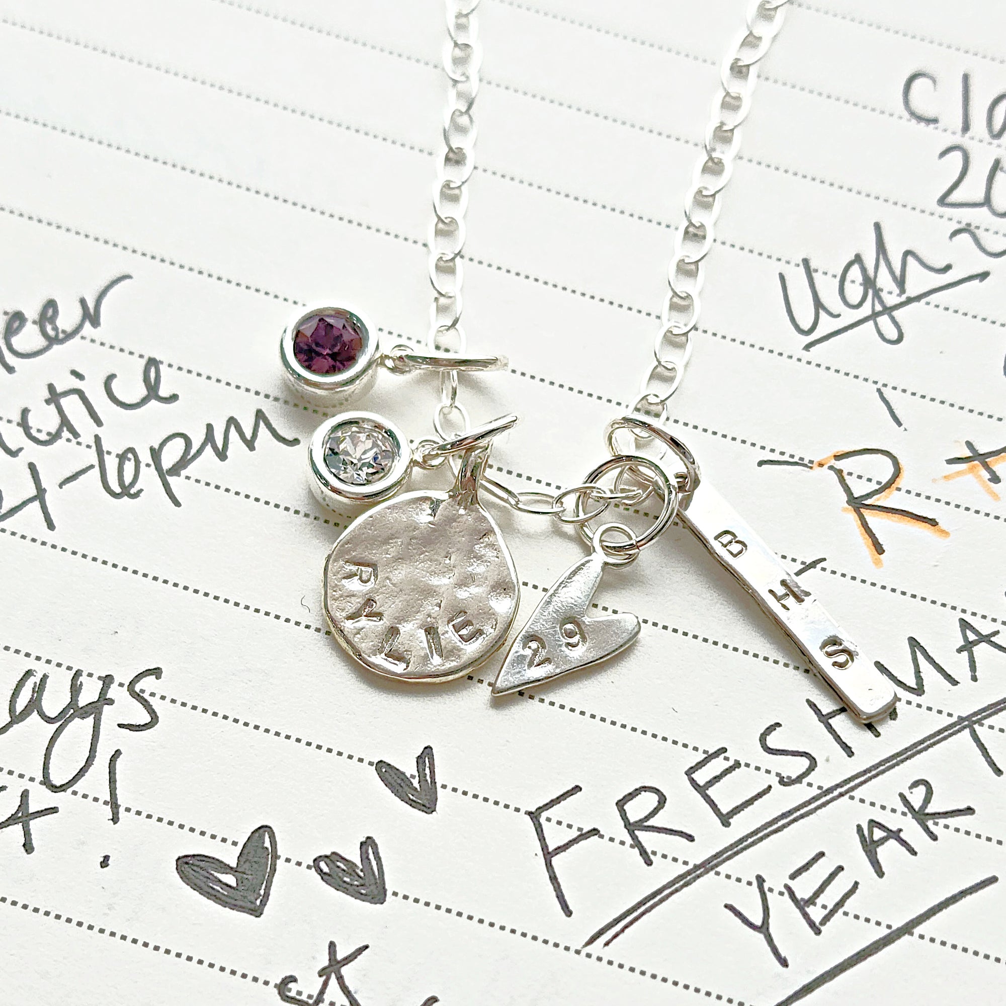 Silver necklace with charms on a piece of paper with writing