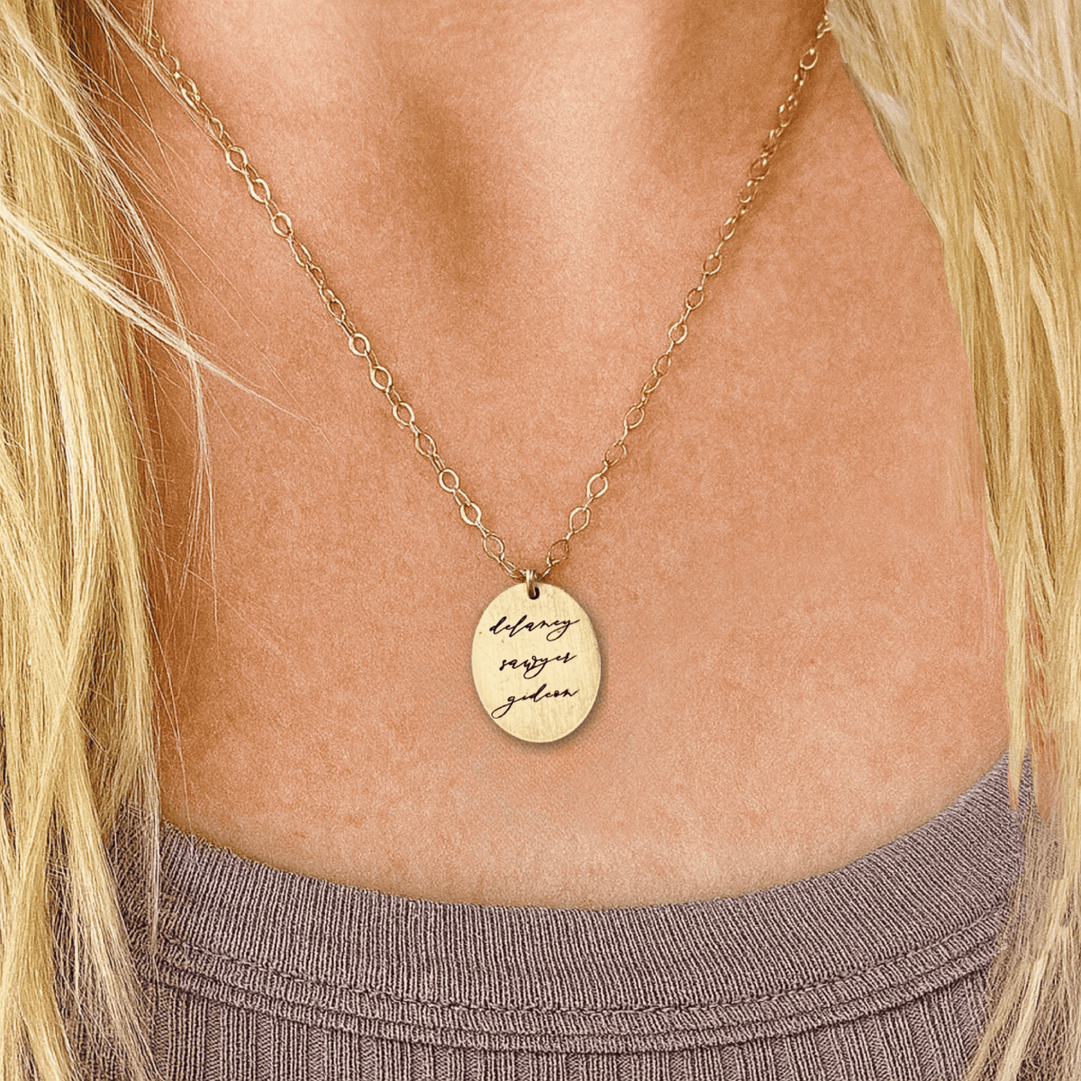 Gold necklace with a pendant on a person wearing a purple top.
