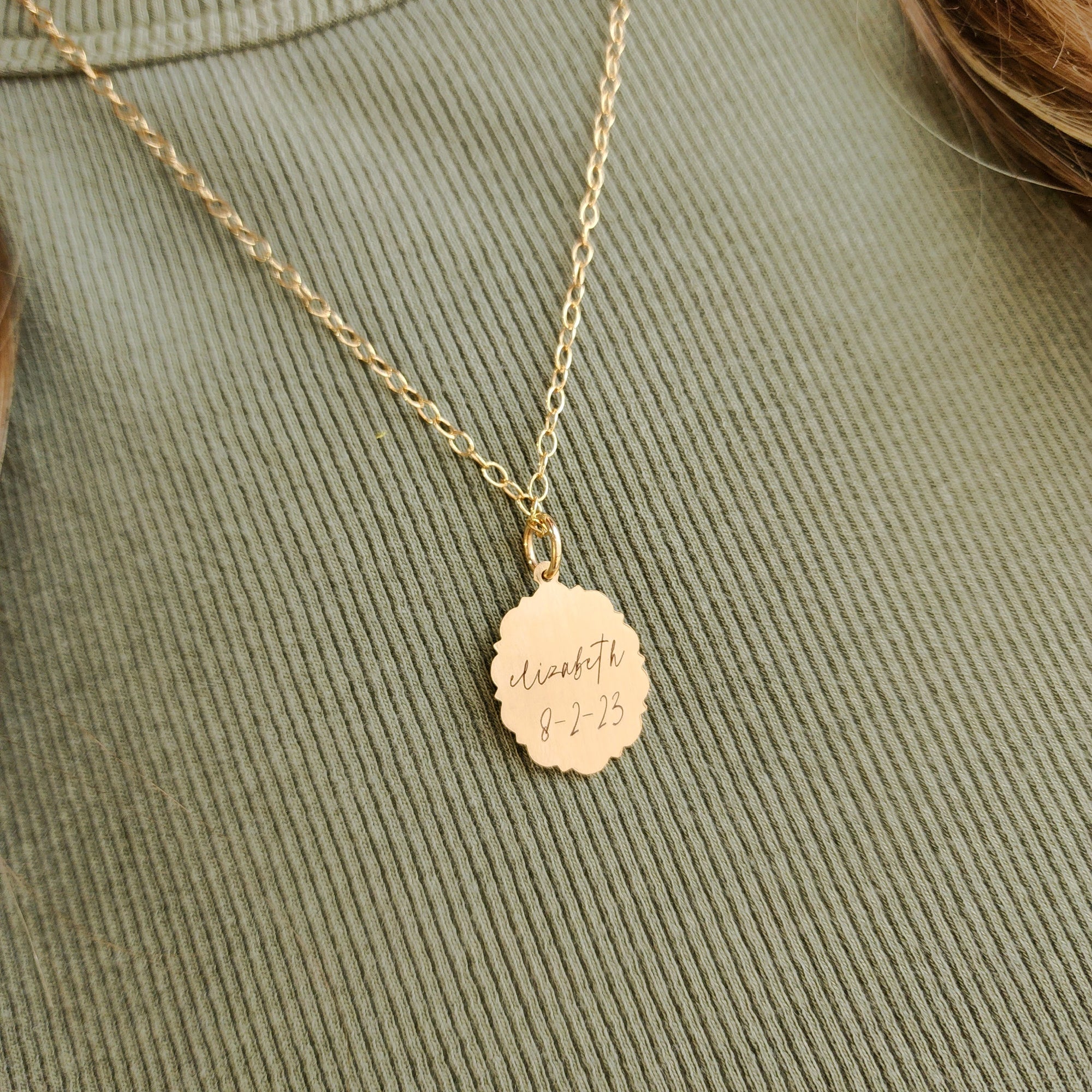 Gold necklace with a round pendant on a green fabric background