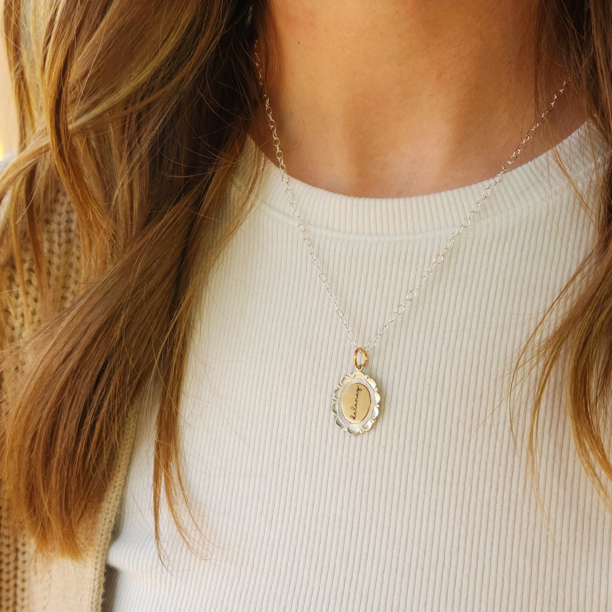 Close-up of a person wearing a gold necklace with a pendant on a plain background