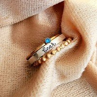 Gold ring with blue gemstone and 'bear' engraving on beige fabric