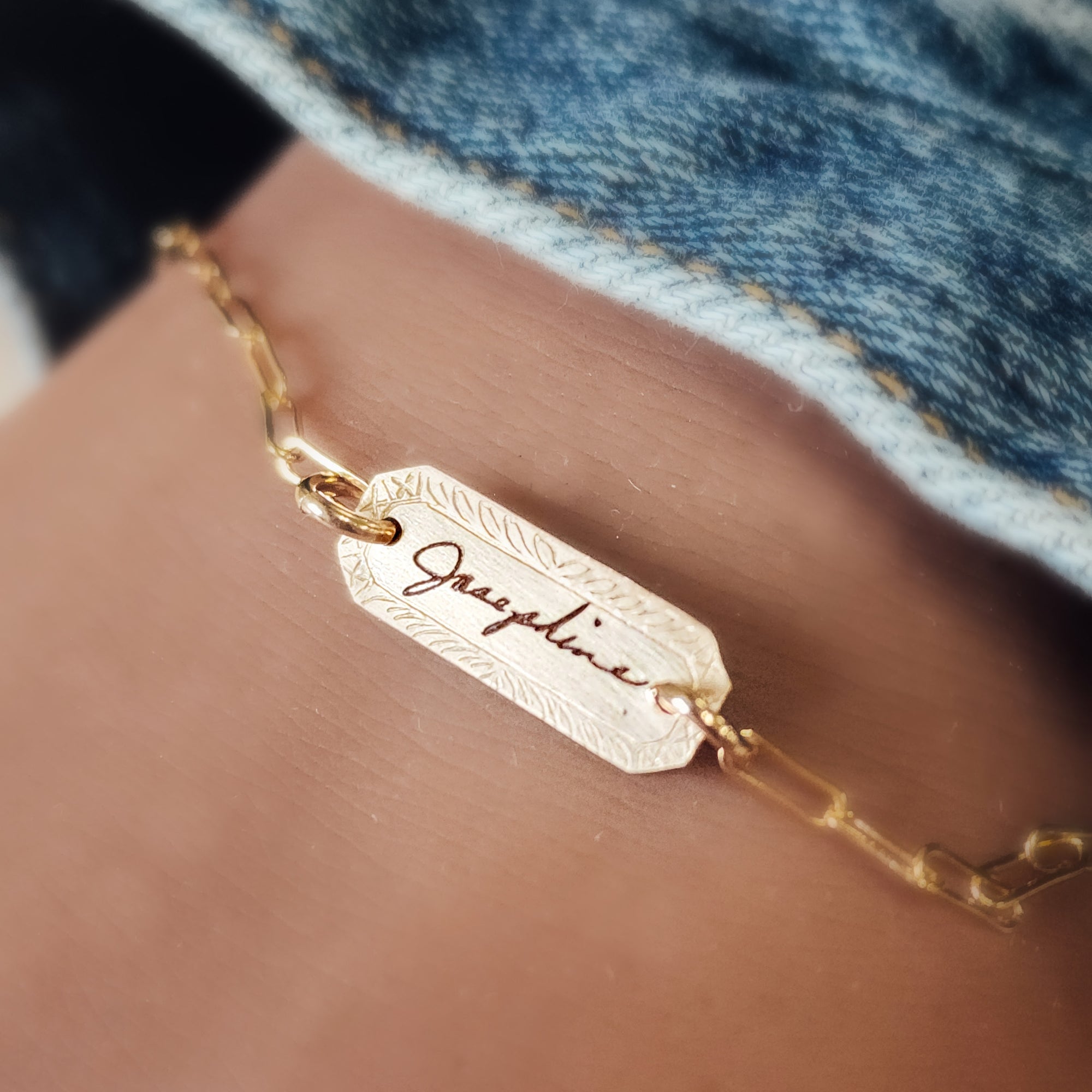 A gold-filled bracelet with a personalized signature tag on a person's wrist, showing the name 'Jessica'.