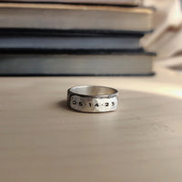 Silver ring with engraved numbers on a stone surface